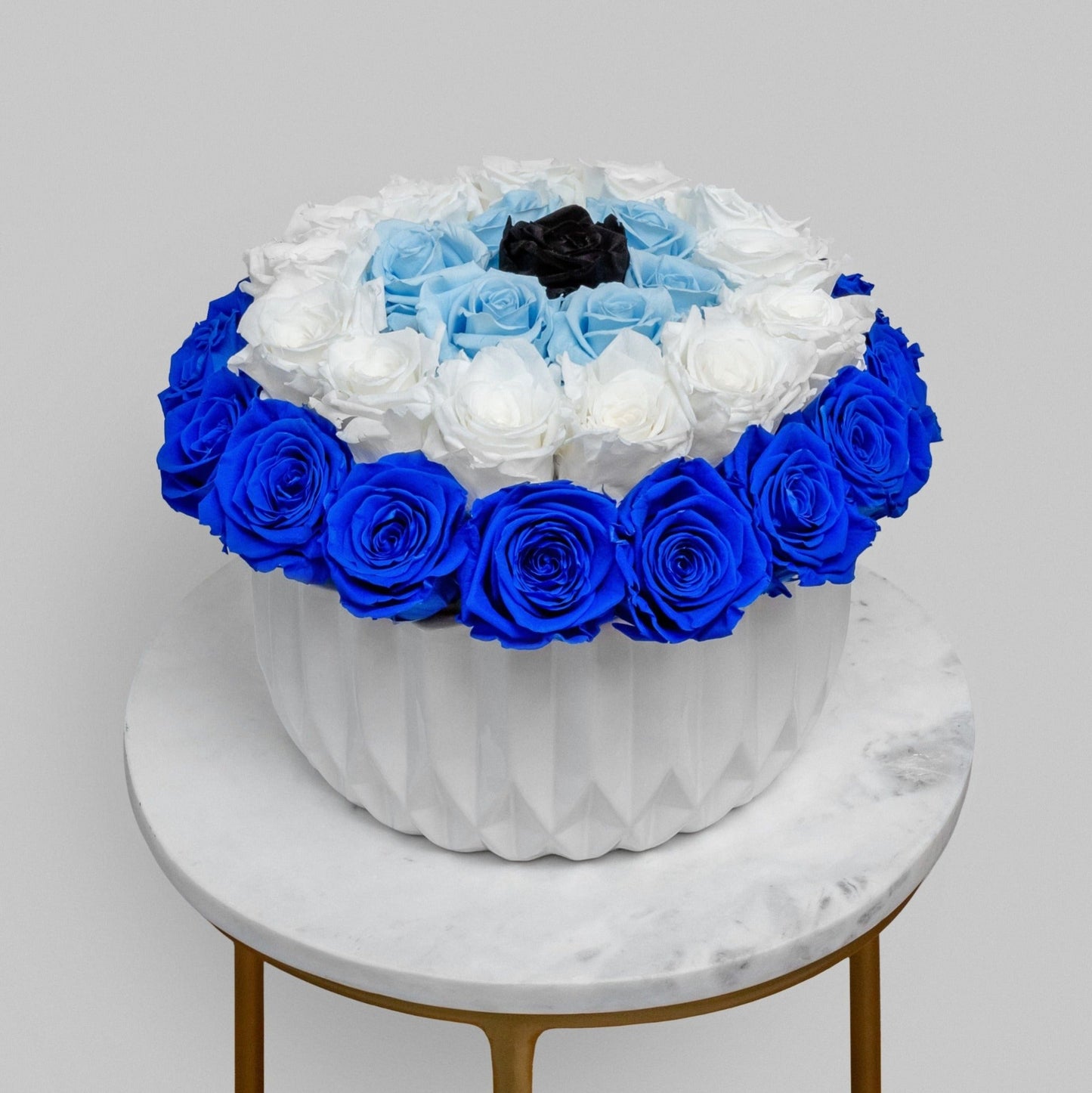 An arrangement of preserved white and blue roses crafted to form the shape of an evil eye